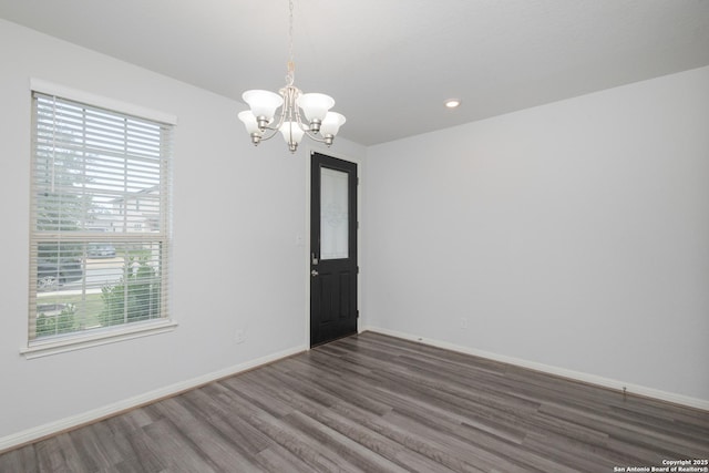 spare room with plenty of natural light, wood finished floors, a chandelier, and recessed lighting