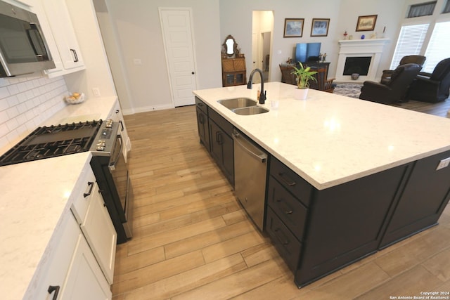 2965 Grove Way, Seguin, TX 78155 - kitchen featuring a sink, appliances with stainless steel finishes, white cabinets, tasteful backsplash, and a fireplace