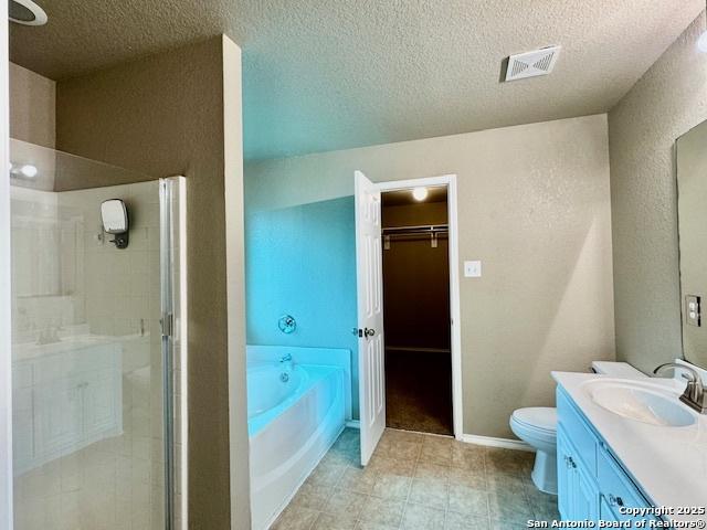 full bathroom with a stall shower, vanity, a textured ceiling, a bath, and toilet