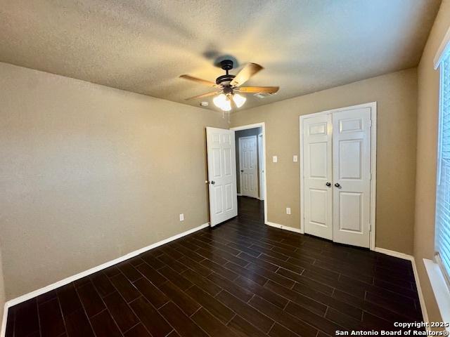 unfurnished bedroom featuring baseboards, dark wood-type flooring, and a ceiling fan