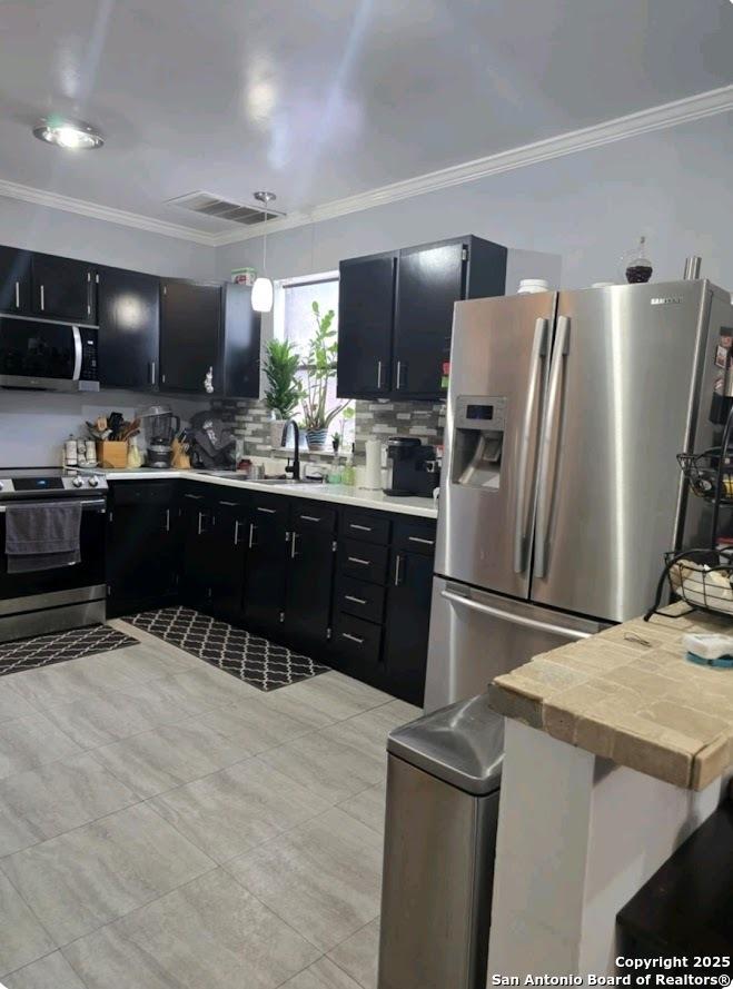 Schertz, TX 78154 - kitchen with appliances with stainless steel finishes, dark cabinets, a sink, ornamental molding, and backsplash