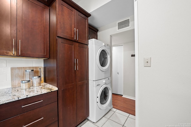 2827 Bent Bow, San Antonio, TX 78209 - clothes washing area featuring stacked washer / drying machine, light tile patterned floors, cabinet space, and baseboards
