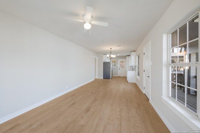 2436 W Woodlawn Ave, San Antonio, TX 78228 - unfurnished living room with a chandelier, light wood-style flooring, baseboards, and ceiling fan