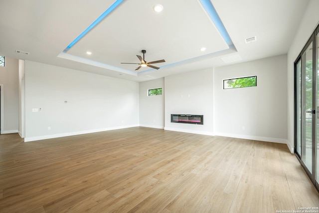25822 Mount Carillon, San Antonio, TX 78260 - unfurnished living room featuring a raised ceiling, a glass covered fireplace, light wood-style flooring, recessed lighting, and baseboards