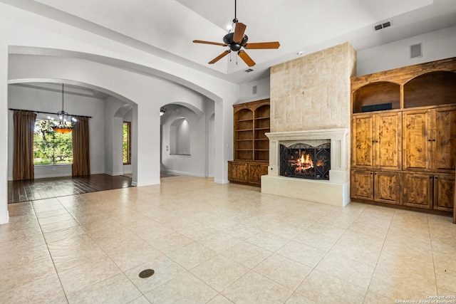 102 Arroyo, Boerne, TX 78006 - unfurnished living room with a chandelier, light tile patterned flooring, arched walkways, a fireplace, and ceiling fan