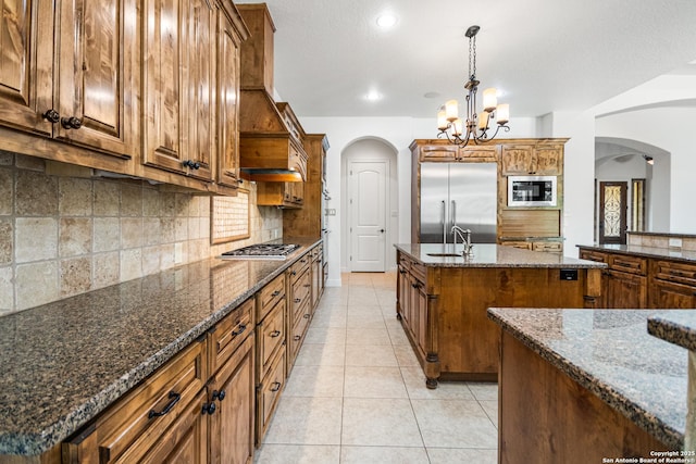 102 Arroyo, Boerne, TX 78006 - kitchen with built in appliances, arched walkways, a center island with sink, a sink, and recessed lighting