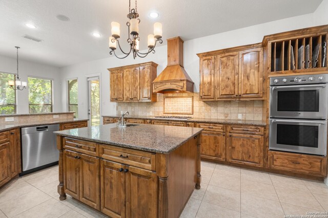 102 Arroyo, Boerne, TX 78006 - kitchen with stainless steel appliances, a chandelier, premium range hood, brown cabinets, and decorative backsplash