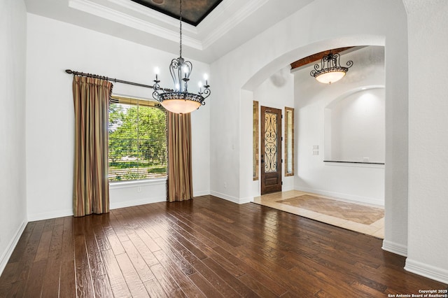 102 Arroyo, Boerne, TX 78006 - spare room featuring wood-type flooring, arched walkways, a tray ceiling, a chandelier, and baseboards