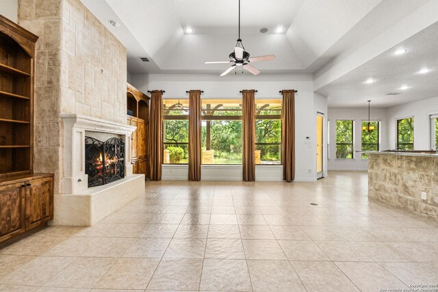 102 Arroyo, Boerne, TX 78006 - unfurnished living room with a large fireplace, a ceiling fan, recessed lighting, a tray ceiling, and light tile patterned floors