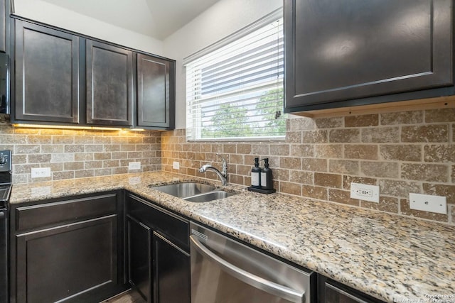 kitchen with stainless steel dishwasher, a sink, tasteful backsplash, and light stone counters