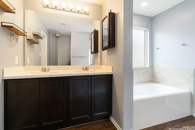 bathroom with wood finished floors, a bath, and double vanity
