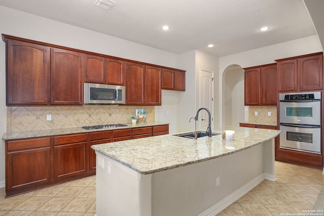 19015 Seminole Pass, Garden Ridge, TX 78266 - kitchen featuring appliances with stainless steel finishes, a sink, arched walkways, light stone counters, and decorative backsplash
