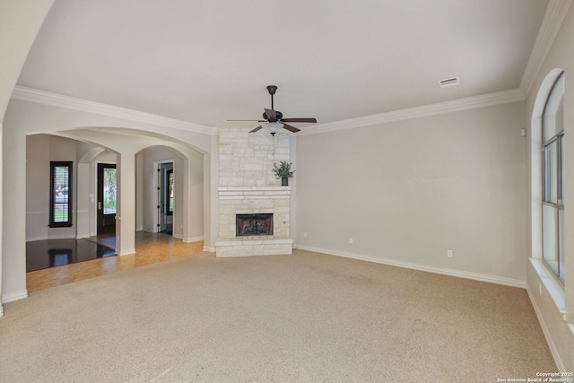 19015 Seminole Pass, Garden Ridge, TX 78266 - unfurnished living room featuring carpet flooring, crown molding, ceiling fan, arched walkways, and a stone fireplace