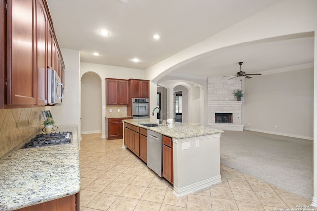 19015 Seminole Pass, Garden Ridge, TX 78266 - kitchen with appliances with stainless steel finishes, a ceiling fan, a sink, a stone fireplace, and decorative backsplash