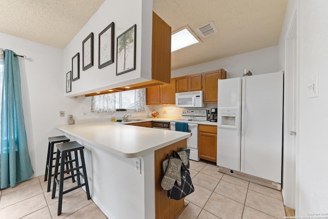 718 Cypressgreen, San Antonio, TX 78245 - kitchen featuring white appliances, a peninsula, light tile patterned floors, light countertops, and a textured ceiling