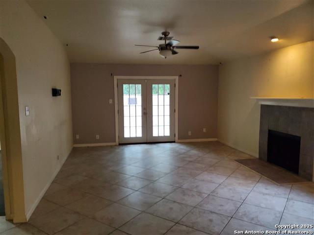 4218 Swan Frst, San Antonio, TX 78222 - unfurnished living room featuring arched walkways, ceiling fan, french doors, and light tile patterned flooring