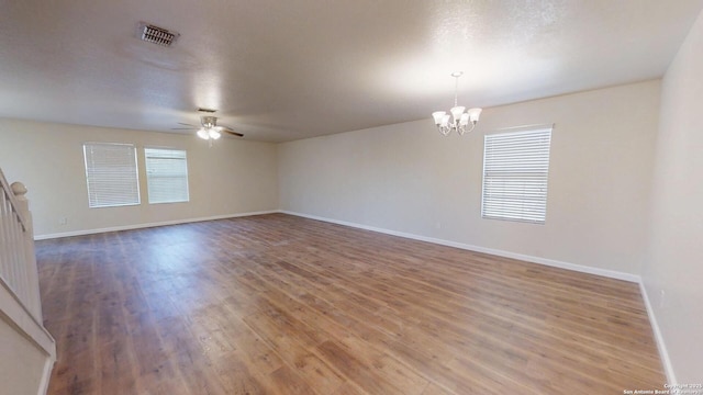 unfurnished room featuring a ceiling fan, wood finished floors, a chandelier, and baseboards