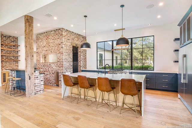 185 Southfield, Boerne, TX 78006 - kitchen featuring light countertops, light wood-type flooring, an island with sink, high end refrigerator, and a breakfast bar