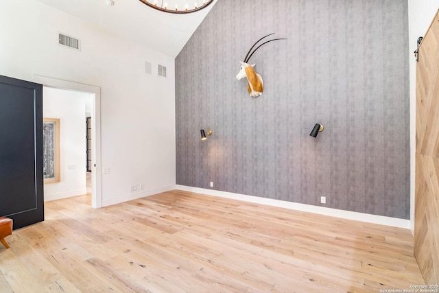 185 Southfield, Boerne, TX 78006 - empty room with wood finished floors, baseboards, wallpapered walls, high vaulted ceiling, and a chandelier