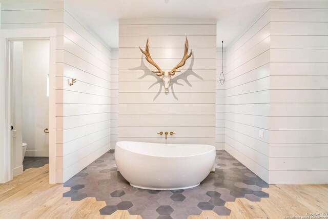 185 Southfield, Boerne, TX 78006 - full bathroom featuring wood finished floors, a freestanding tub, wood walls, and toilet