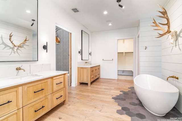 185 Southfield, Boerne, TX 78006 - bathroom with wood-type flooring, two vanities, a soaking tub, and recessed lighting