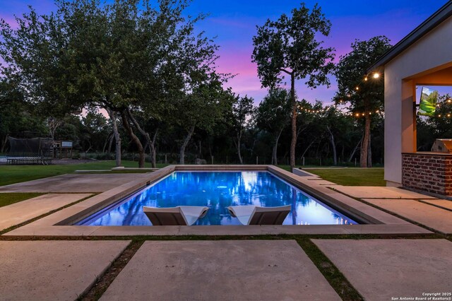 185 Southfield, Boerne, TX 78006 - pool at dusk featuring a patio area, an outdoor pool, a trampoline, and a yard