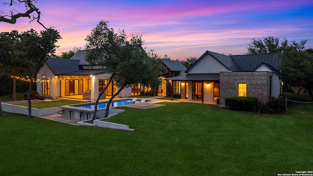 185 Southfield, Boerne, TX 78006 - back of house at dusk with a standing seam roof, a patio, metal roof, and a yard