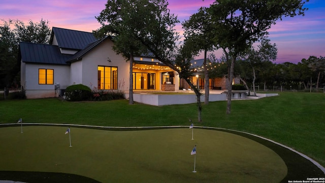 185 Southfield, Boerne, TX 78006 - rear view of house with an area to practice putting, a standing seam roof, stucco siding, and a lawn