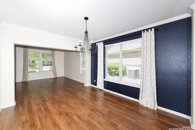 spare room featuring a chandelier, ornamental molding, wood finished floors, and baseboards