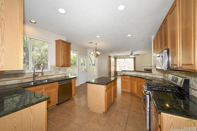 kitchen featuring appliances with stainless steel finishes, a sink, recessed lighting, decorative backsplash, and dark stone countertops