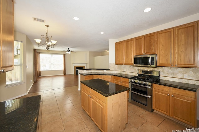 kitchen with appliances with stainless steel finishes, tasteful backsplash, dark stone counters, a chandelier, and recessed lighting