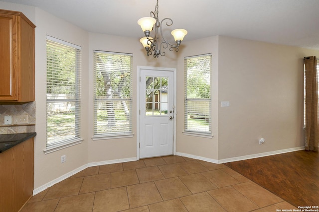 doorway with a chandelier, healthy amount of natural light, and tile patterned floors