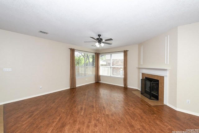 unfurnished living room with a ceiling fan, wood finished floors, a fireplace, baseboards, and a textured ceiling
