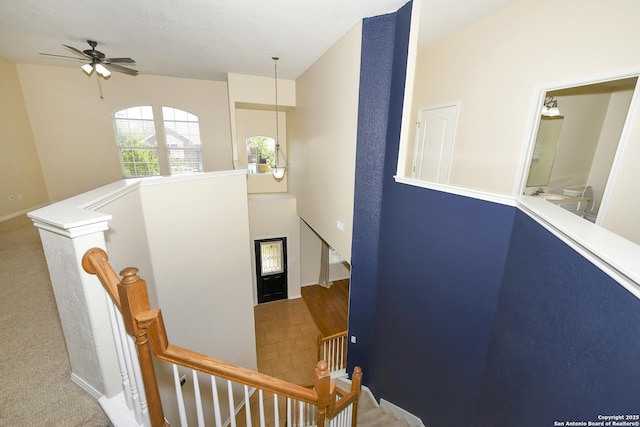 staircase with ceiling fan and baseboards