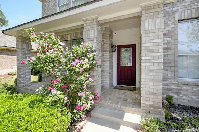 property entrance featuring brick siding and a porch