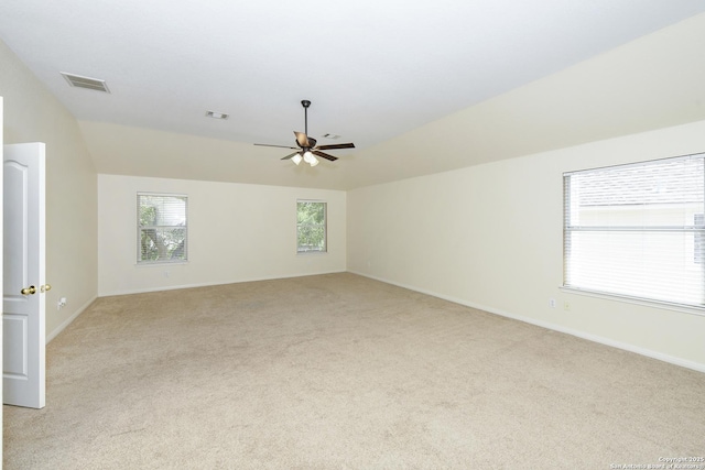 empty room featuring light colored carpet, lofted ceiling, ceiling fan, and baseboards