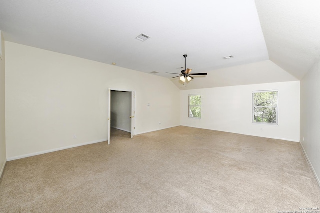 empty room with light carpet, vaulted ceiling, a ceiling fan, and baseboards