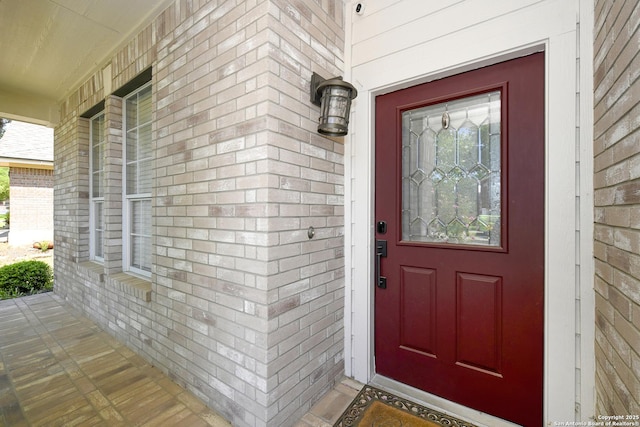 entrance to property featuring covered porch and brick siding