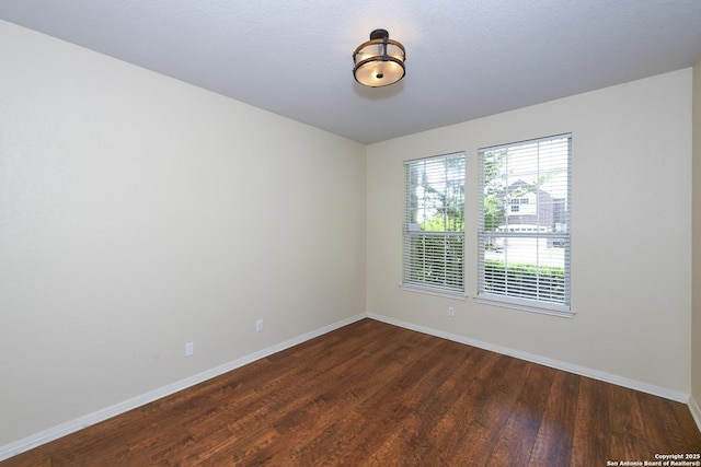 empty room with dark wood-style flooring and baseboards
