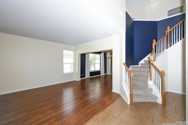 foyer with stairs, ornamental molding, baseboards, and wood finished floors