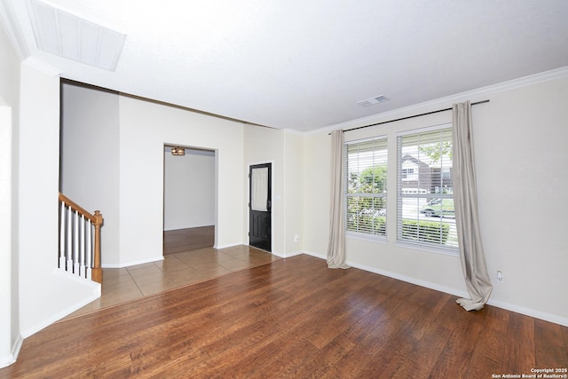spare room with wood finished floors, ornamental molding, baseboards, and stairs
