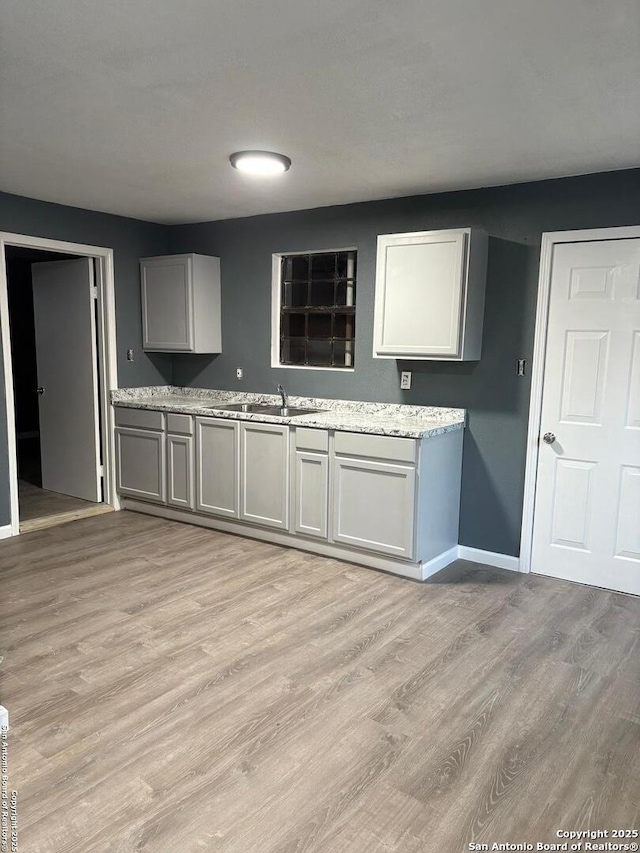919 Palo Alto, San Antonio, TX 78211 - kitchen with a sink, light wood-style floors, baseboards, and gray cabinetry