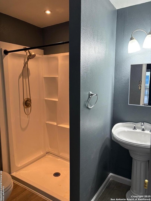 919 Palo Alto, San Antonio, TX 78211 - bathroom featuring wood finished floors, a stall shower, a textured wall, baseboards, and toilet