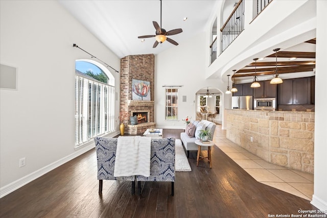 12627 Alamito Crk, San Antonio, TX 78254 - living room with arched walkways, a ceiling fan, wood finished floors, a fireplace, and high vaulted ceiling