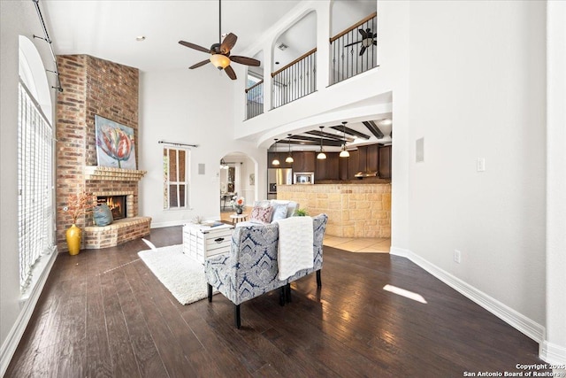 12627 Alamito Crk, San Antonio, TX 78254 - living area with wood finished floors, ceiling fan, a fireplace, baseboards, and a towering ceiling