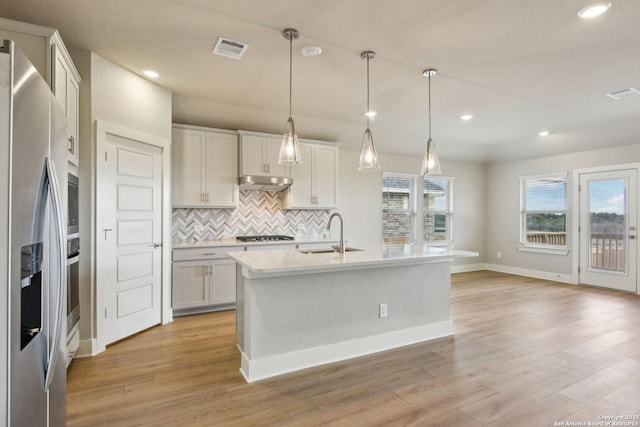 12734 Tegea Pass, San Antonio, TX 78245 - kitchen featuring stainless steel appliances, a sink, tasteful backsplash, light wood-style flooring, and light countertops