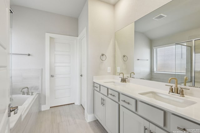 12734 Tegea Pass, San Antonio, TX 78245 - bathroom featuring a relaxing tiled tub, double vanity, and a shower with shower door