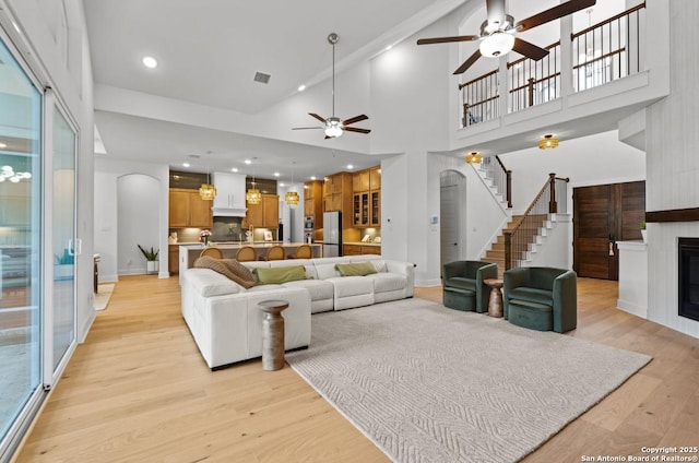 4003 Wood Crk, San Antonio, TX 78257 - living room featuring a ceiling fan, stairway, a large fireplace, light wood-type flooring, and baseboards