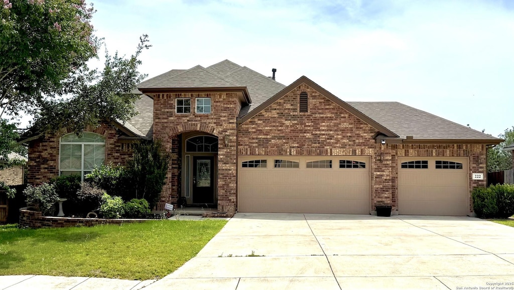 222 Red Quill Nest, San Antonio, TX 78253 - french country style house with a garage, a shingled roof, brick siding, and driveway