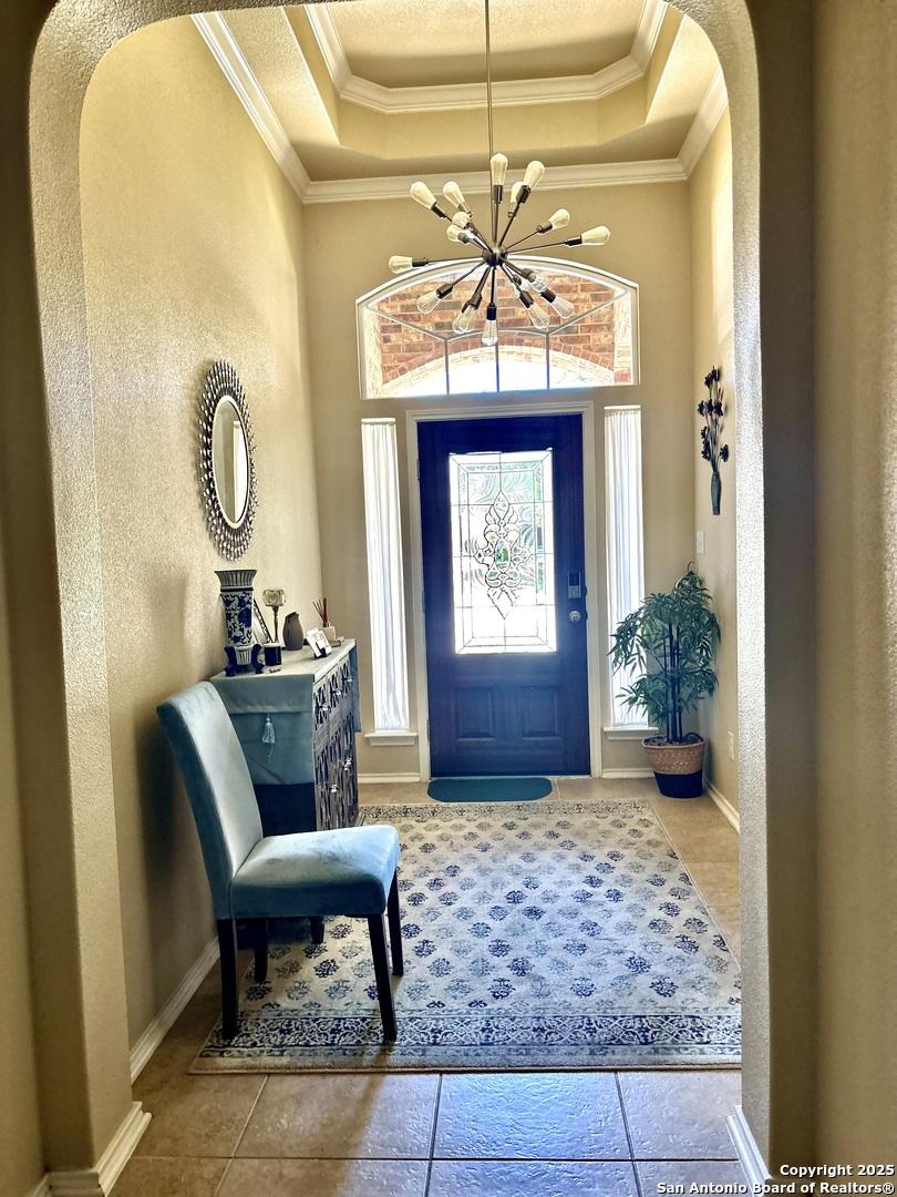 222 Red Quill Nest, San Antonio, TX 78253 - foyer with a raised ceiling, arched walkways, tile patterned flooring, crown molding, and a chandelier